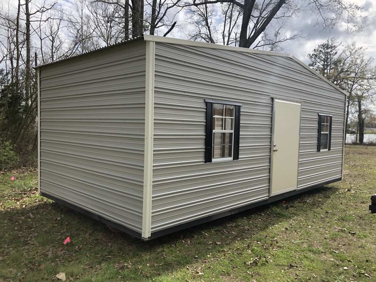 Gray aluminum shed with black shutters