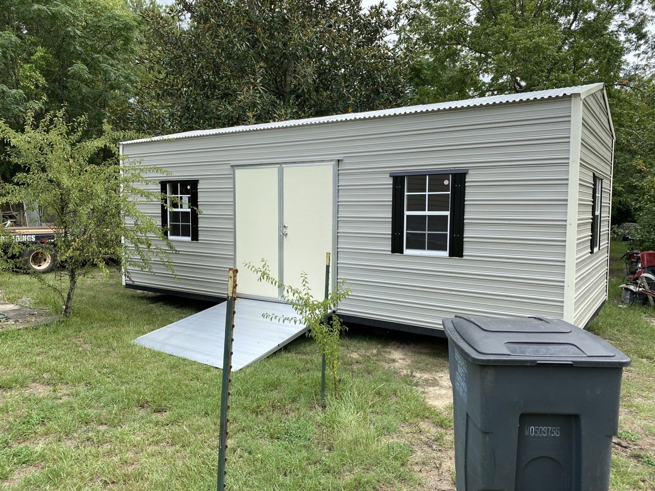 Gray aluminum shed with black shutters and ramp
