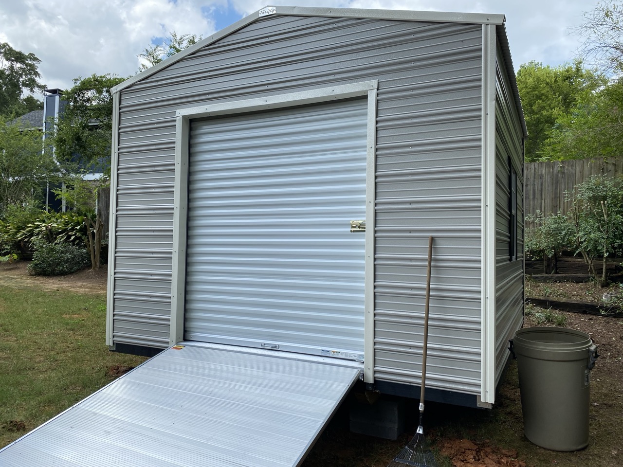 Gray aluminum shed with roll-up door and ramp