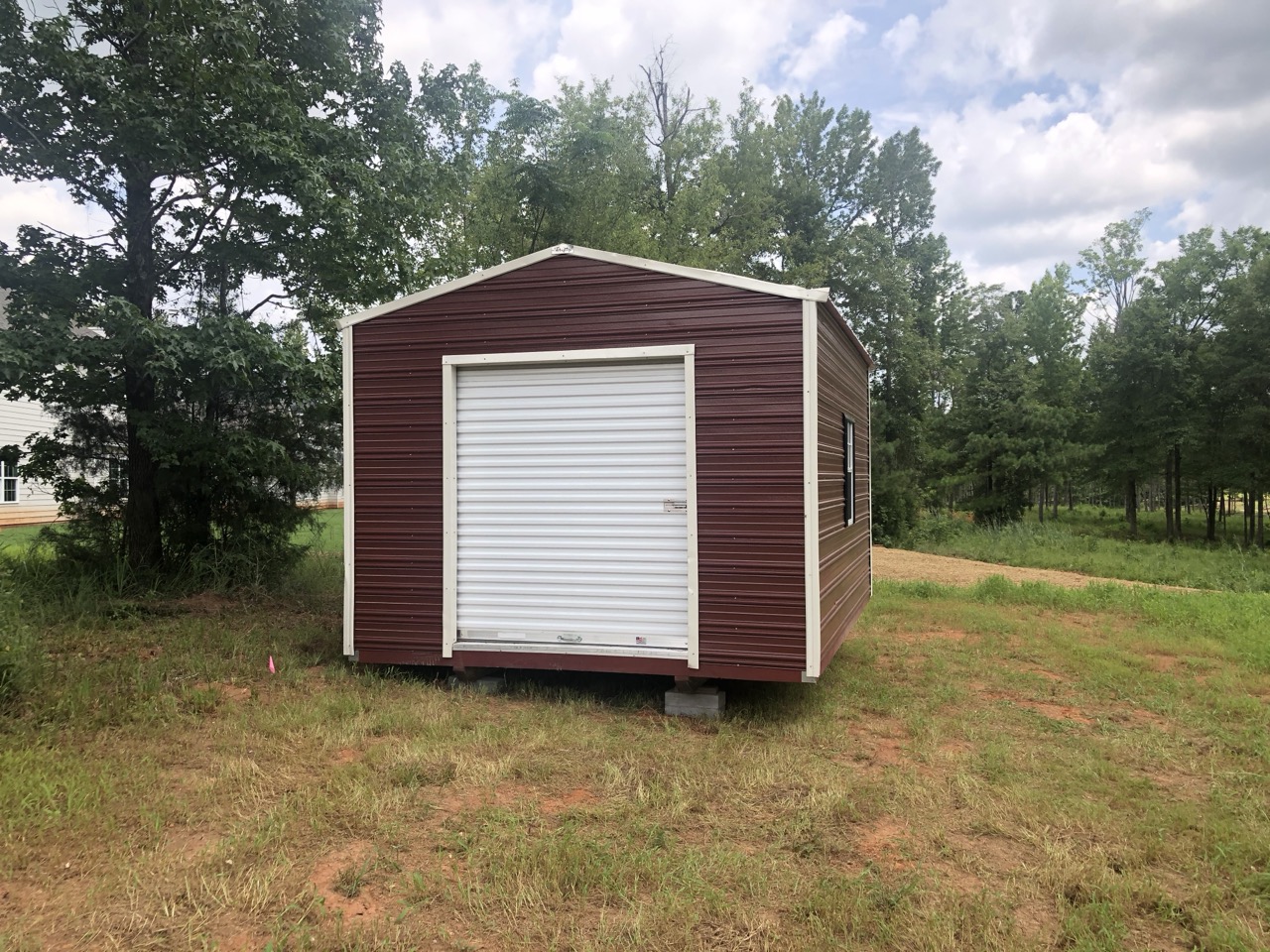 Maroon aluminum shed with roll-up door