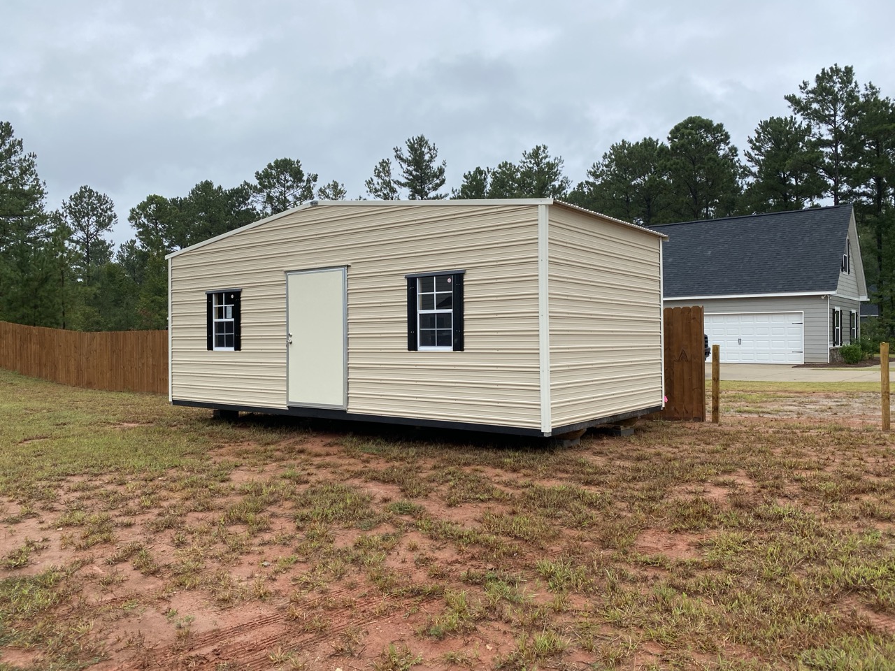 Tan aluminum shed with black shutters