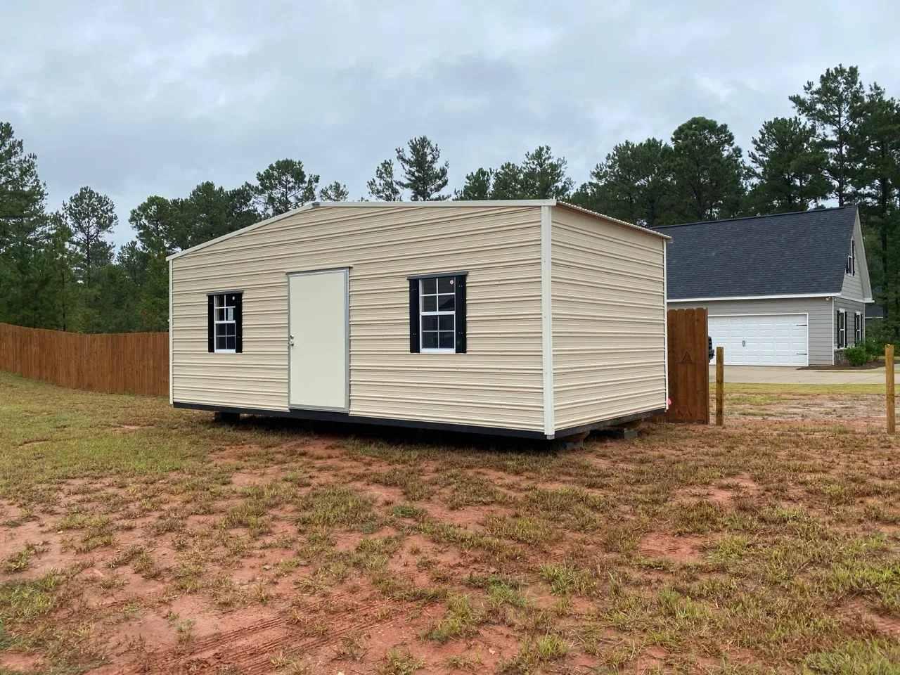 Tan aluminum shed with black shutters