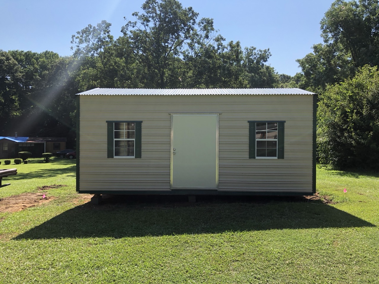 Tan aluminum shed with green trim