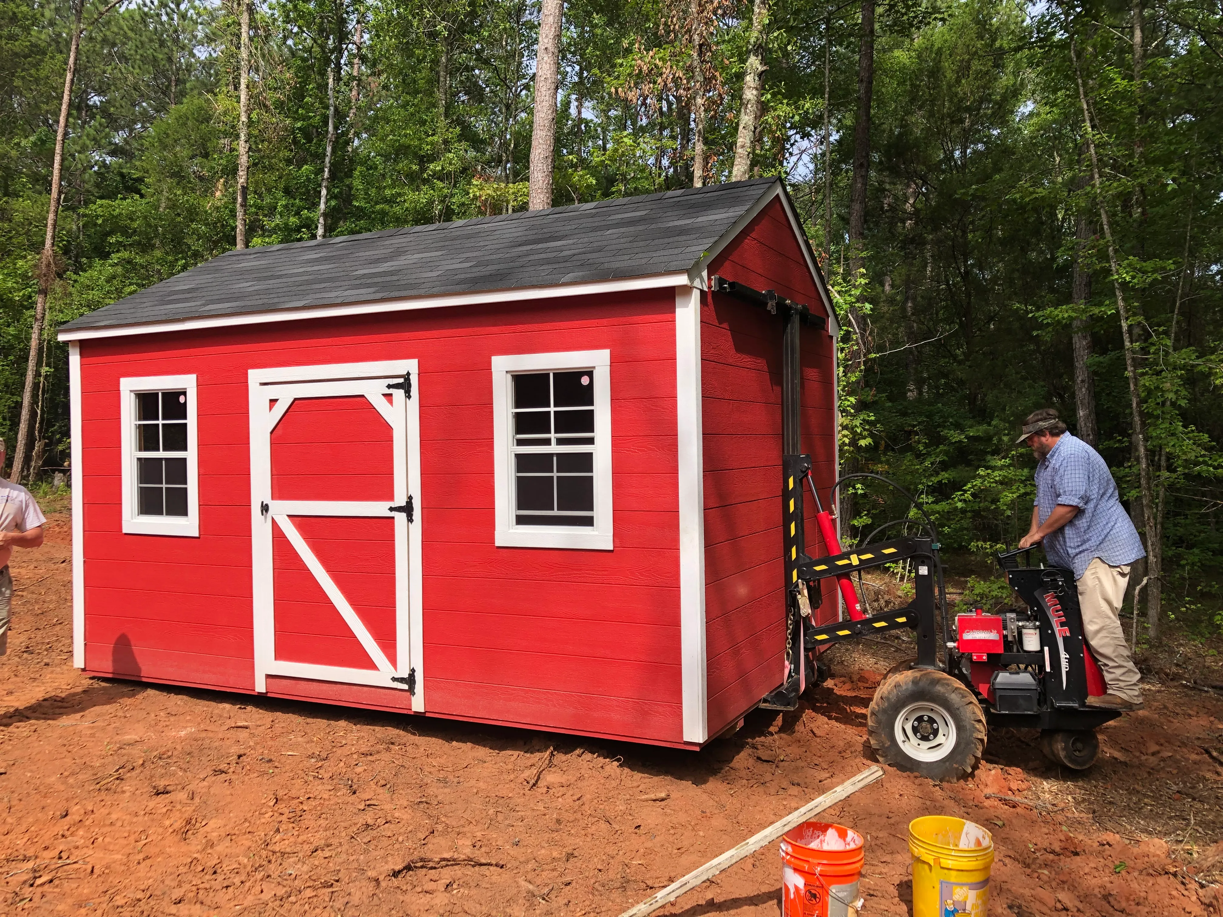 Operator using mule to move a red wood shed